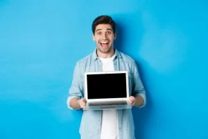 cheerful-smiling-man-making-presentation-showing-laptop-screen-looking-happy-standing-blue-background_1258-65256